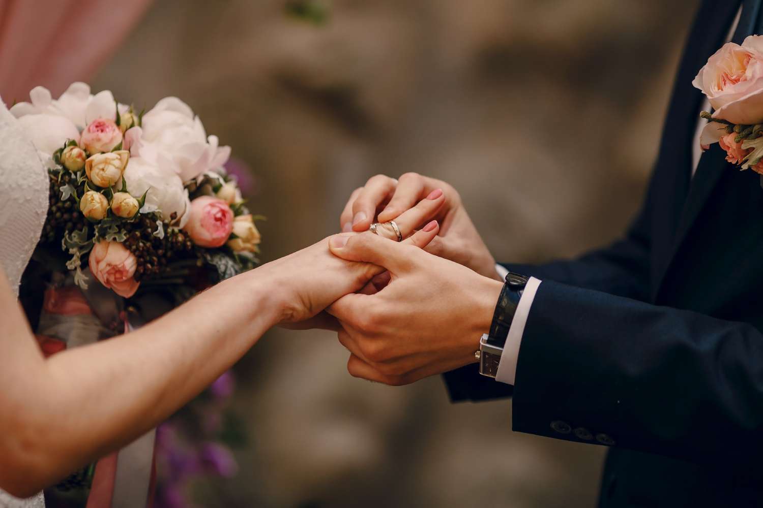 Bride and groom exchanging rings surrounded by a bouquet at a Westfield Country Club wedding